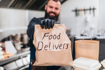 The chef prepares food in the restaurant and packs it.  Food in disposable dishes and bag of craft paper ready for delivery.