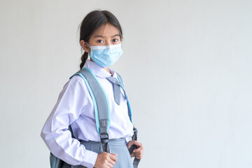 Portrait of a cheerful child student wears a face mask isolated on white background smiles and looks at the camera. Back to School Concept Stock Photo