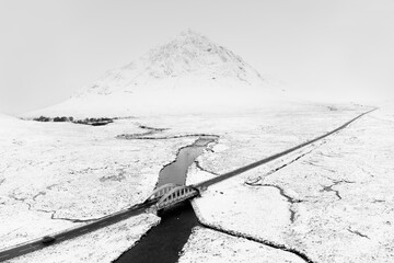 Buachaille Etive Mor mountain and empty road covered in snow during winter