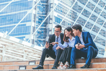 Young business team sitting on stairs and selfie with cityscape background.