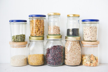 Dry cereals and seeds in glass jars, the concept of healthy nutrition (beans, quinoa, pumpkin seeds, sesame seeds, raisins, pasta).