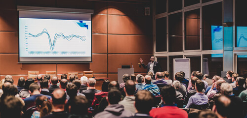 Business speaker giving a talk in conference hall.