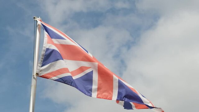 A Union Jack Flag flying from a flag pole in the sky, United Kingdom
