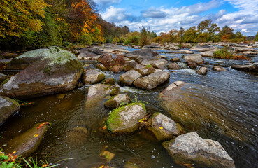 Fototapeta na wymiar Autumn river with beautiful large stones, blue sky and trees
