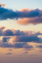 Natural background, stunning view of some fluffy clouds on a purple and orange sky during a beautiful sunrise. Sardinia, Italy.
