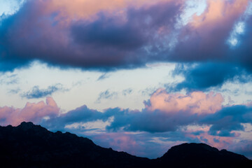 Stunning view of a dark, shadowy mountain range during a dramatic and cloudy sunrise. San Pantaleo, Sardinia, Italy.