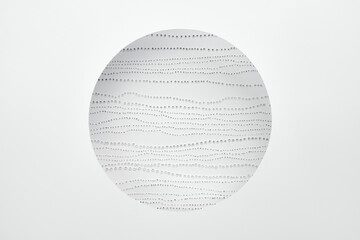 White paper background. Round hole and dot pattern underneath.