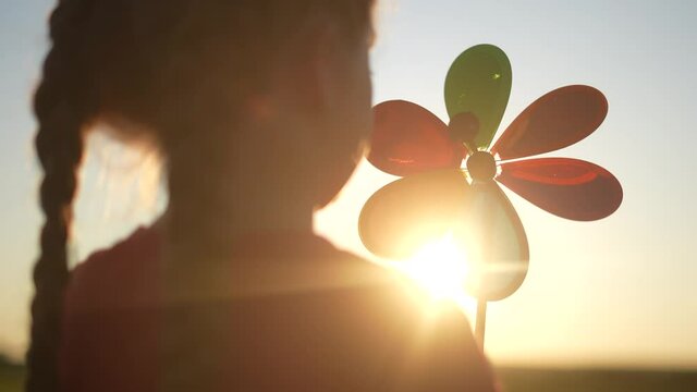 kid pinwheel. little baby girl silhouette play with windmill toy wind in the park. happy family kid dream concept. baby girl play toy pinwheel the glare sunset fun of the sun at in the park