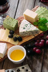 Cheese plate on a dark background. Brie, dor blue, gouda, grapes, nuts, wine