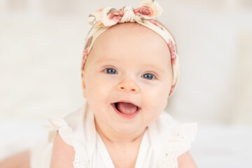 portrait of a baby girl smiling or laughing lying on a white cotton bed at home