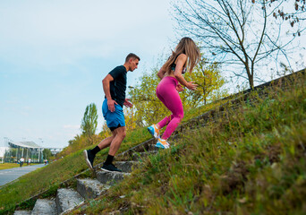 Woman and man jogging on upstairs in the city park together