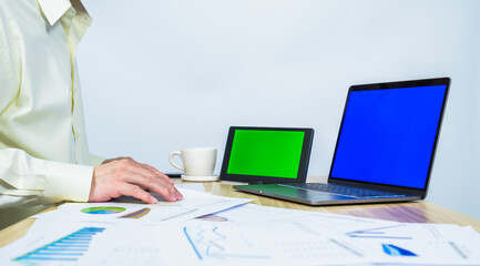 man working, tablet green screen, laptop blue screen, document graph