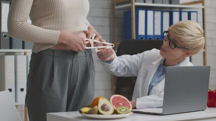Doctor nutritionist measuring body fat index for young woman patient before making treatment plan, sitting at office
