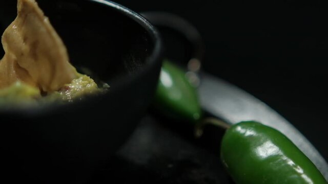 Bowl of guacamole on Mexican comal decorated with tortilla chips and vegetables