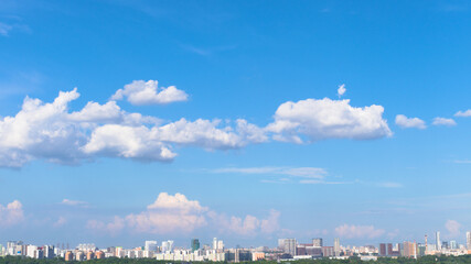 Bright background with blue sky and white clouds and urban Moscow buildings on the horizon
