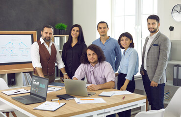 Portrait of a friendly, positive and successful team of employees in the office. Diverse men and women work together on a business project. Concept of teamwork, business, people and partnership.