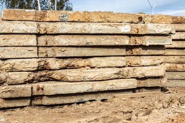 Old reinforced concrete road slabs stacked on a construction site for later use. Temporary road surface.