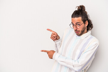 Young caucasian man isolated on gray background pointing with forefingers to a copy space, expressing excitement and desire.