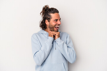 Young caucasian man isolated on gray background keeps hands under chin, is looking happily aside.