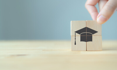 Obraz na płótnie Canvas Graduation from university, education, diploma concept. Happiness cheerful feeling, Commencement, Graduation day. Hand hold wooden cube with graduation cap on beautiful grey background and copy space.