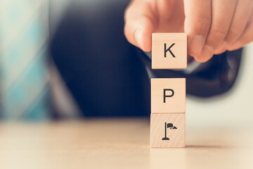 Banner KPI concept. Key Performance Indicator using business intelligence metrics to measure achievement versus planned target.  Businessman hold wooden cubes with "KPI" letters Beautiful background.