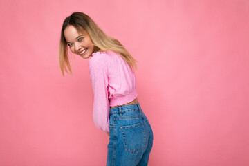 Young beautiful woman. Trendy woman in fashionable pink crop top. Positive female shows facial emotions. Funny model isolated on pink background with free space