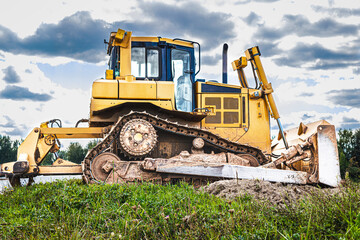 Bulldozer machine is leveling construction site. Earthmover with tractor is moving earth. Close-up. Construction heavy machinery.