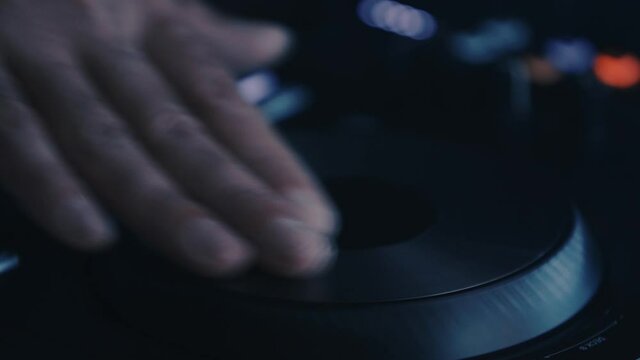 Disc jockey scratching tracks with turntable device on stage in nightclub. Professional hip hop dj scratches with midi controller on party in night club