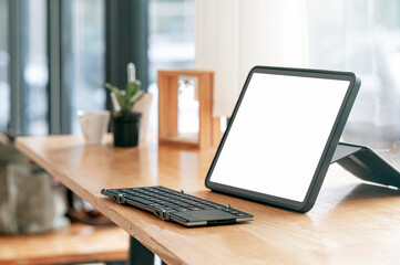 Mockup portable blank screen tablet and keyboard on wooden table with  copy space.