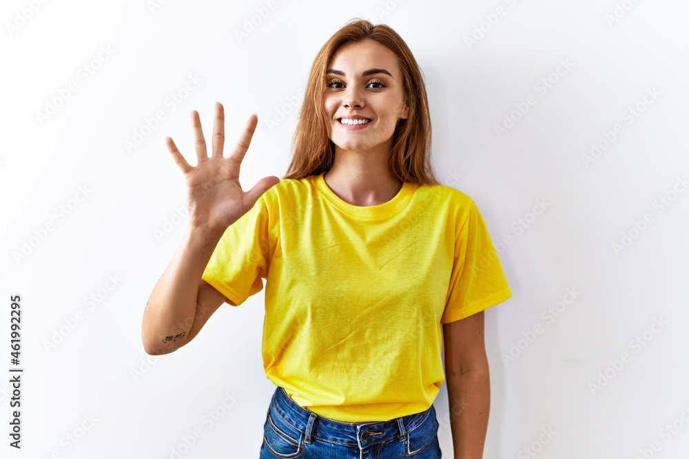 Poster young brunette woman standing over isolated background showing and pointing up with fingers number f