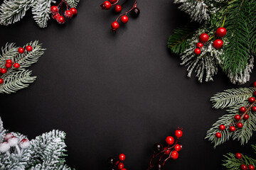Christmas holidays composition with red berries and fir tree branches on black background with copy...
