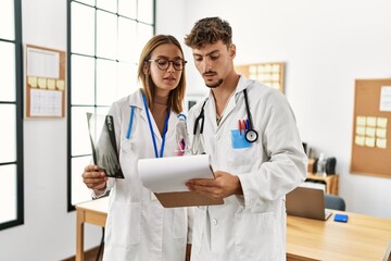 Two hispanic doctor working in a medical meeting looking bone scan at the clinic office.