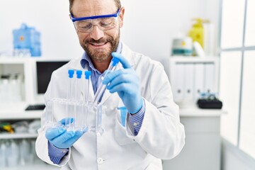 Middle age hispanic man wearing scientist uniform working at laboratory