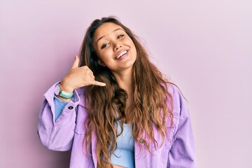 Fototapeta premium Young hispanic girl wearing casual clothes smiling doing phone gesture with hand and fingers like talking on the telephone. communicating concepts.