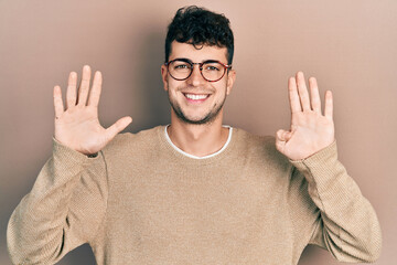Young hispanic man wearing casual clothes and glasses showing and pointing up with fingers number...