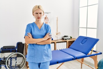 Beautiful caucasian physiotherapist woman working at pain recovery clinic skeptic and nervous, disapproving expression on face with crossed arms. negative person.