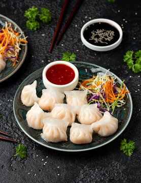 Traditional Asian Prawn or shrimp dumplings hakau, ha kauw or har gow. Served with cabbage, carrot salad and soy and sweet chilli sauce