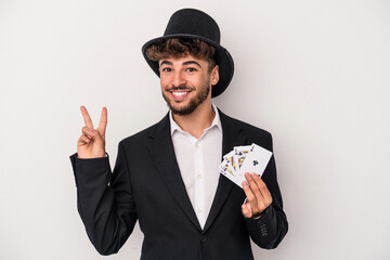 Young arab wizard man holding a magic cards isolated on white background joyful and carefree...