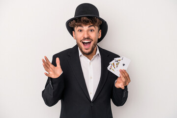 Young arab wizard man holding a magic cards isolated on white background receiving a pleasant...