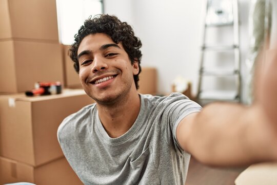 Young hispanic man smiling happy making selfie by the camera at new home.