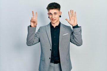 Young caucasian boy with ears dilation wearing business jacket showing and pointing up with fingers number seven while smiling confident and happy.