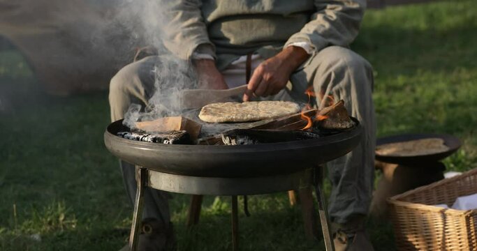 Man baking bread on open fire