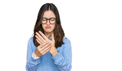 Young beautiful woman wearing casual clothes and glasses suffering pain on hands and fingers,...