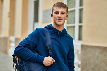 Young blond student smiling happy standing at the university.