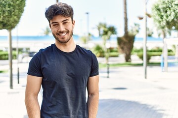 Young hispanic man smiling happy standing at the city.