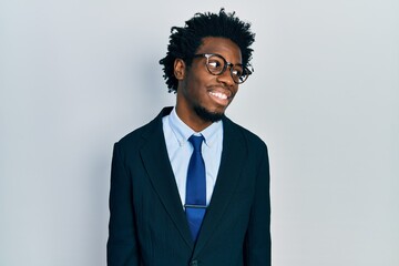 Young african american man wearing business suit looking away to side with smile on face, natural expression. laughing confident.