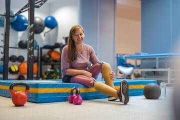 Young woman with prosthetic legs exercising at physiotherapy center
