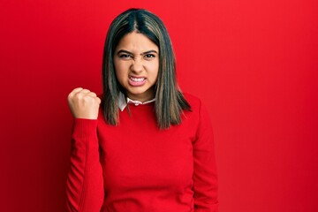 Young latin woman wearing casual clothes angry and mad raising fist frustrated and furious while shouting with anger. rage and aggressive concept.
