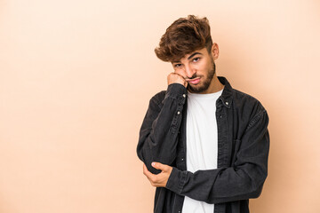 Young arab man isolated on beige background who feels sad and pensive, looking at copy space.