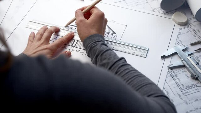 Woman architect draws a sketch of a house on paper. A designer is working on a construction project at his desk. Blueprints.